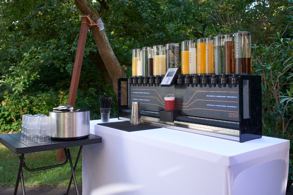 Cocktailmaschine auf einem Bartisch mit weißer Husse im Garten